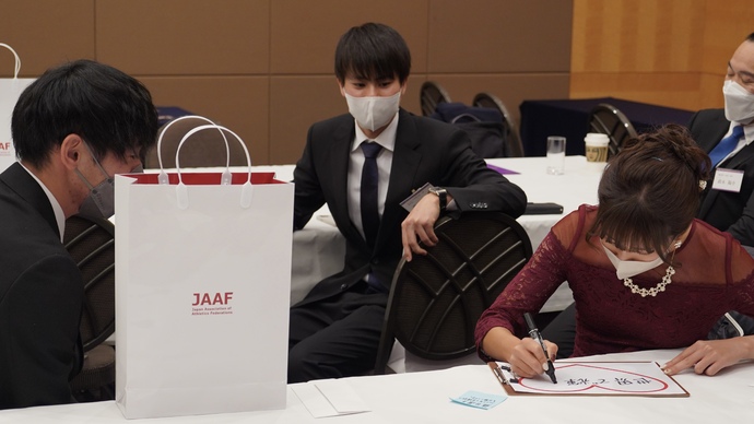 【陸連アワードの舞台裏】藤井菜々子選手は色紙に抱負を記載中:住所大翔選手と池田向希選手が見守ります